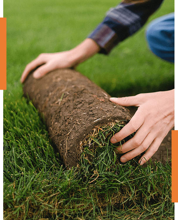 A person is rolling a log in the grass.