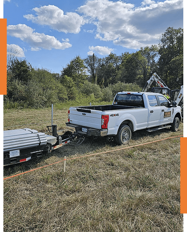 A white truck pulling a trailer with a crane on it.