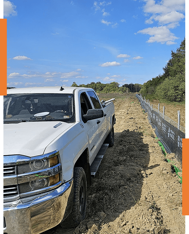 A white truck parked on top of a dirt road.