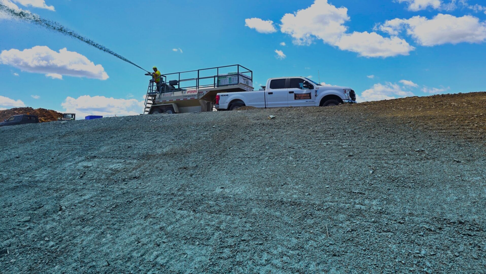 Truck spraying green on a hillside.