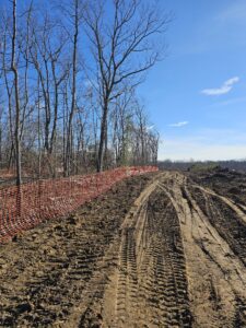 Tire tracks in a dirt field with trees.