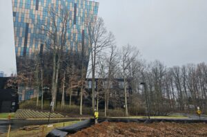 A worker stands near a modern glass building.