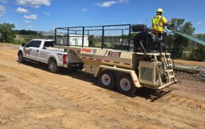 White truck hauling hydro seeder.