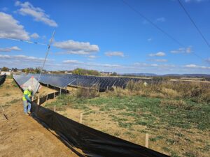 Worker installing solar panels in field.