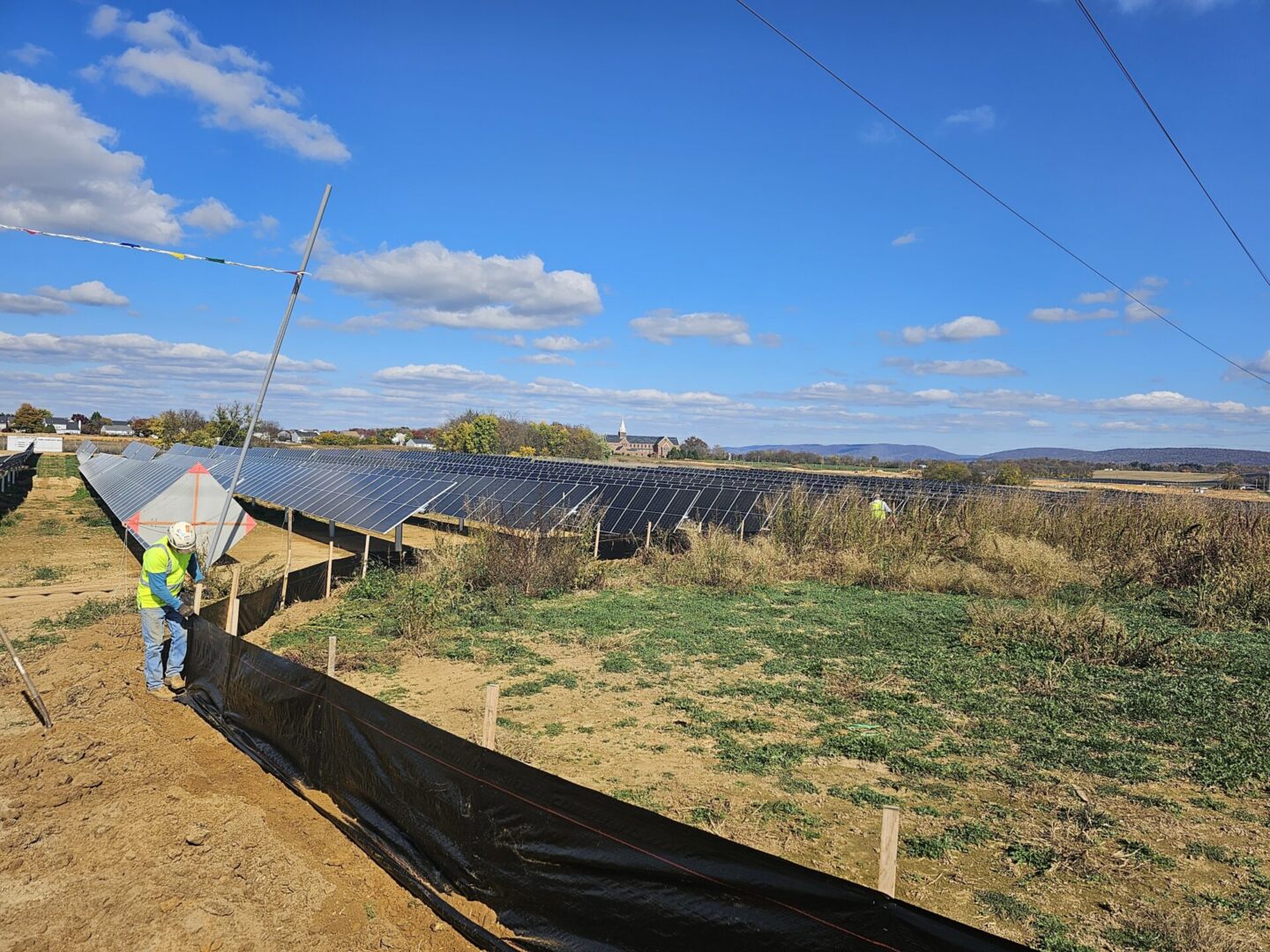 A worker installing solar panels in a field.