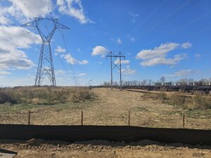 Power lines and solar panels in field.