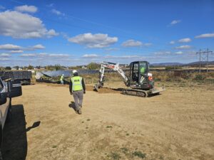 Construction workers and excavator at a solar farm.